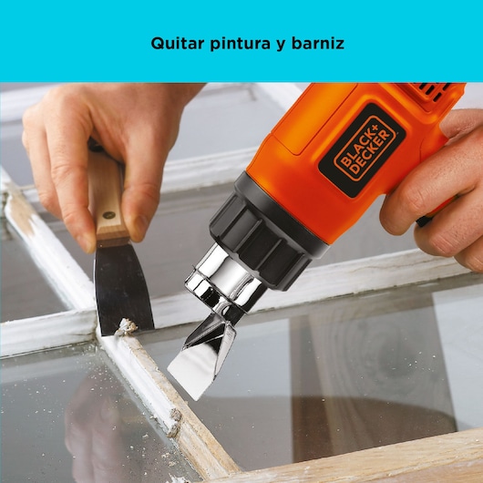 BLACK+DECKER HG1500 heat gun used to remove paint from a window frame with a scraper.
