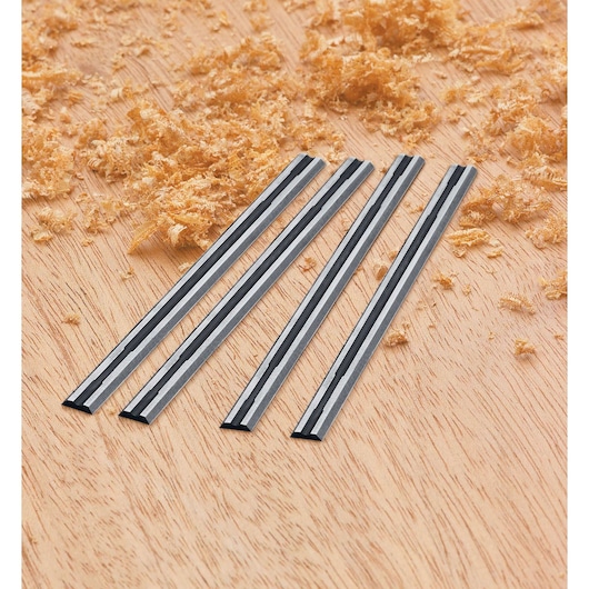 BLACKDECKER 7698K photography of four metal planer blades on wood surface with sawdust, angled view.