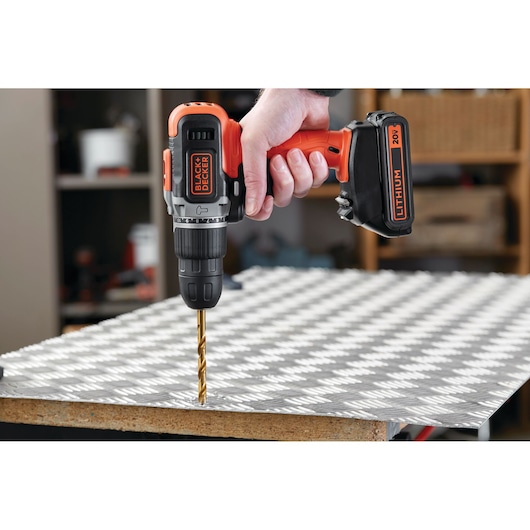 Photo of BLACKDECKER cordless drill BCK21S1S with 20V lithium battery drilling into metal sheet.