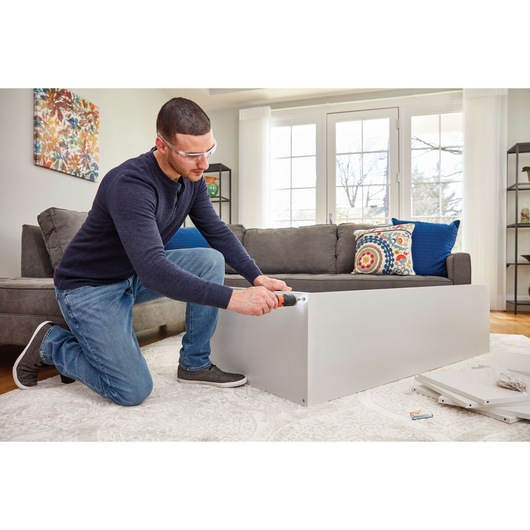 Photo of person assembling furniture with BLACKDECKER BCF601AA cordless screwdriver in living room.