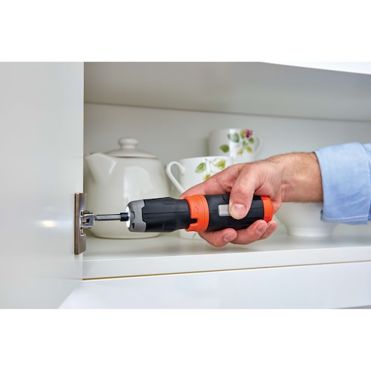 BLACKDECKER BCF601AA cordless screwdriver used to attach cabinet hinge, tea set in background.