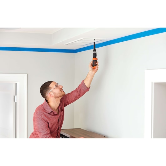 BLACKDECKER BCF601AA cordless screwdriver held by person installing vent cover on ceiling indoors.