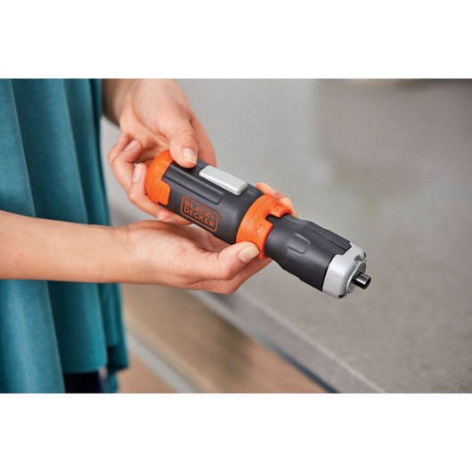 Photo of BLACK+DECKER BCF601AA cordless screwdriver, black and orange, shown held in hand near countertop.