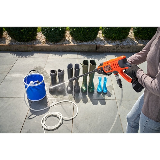 Photo of BLACKDECKER BCPW350E1 pressure washer cleaning boots outdoors with blue bucket and hose visible.