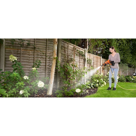 Photo of BLACKDECKER BCPW350E1 pressure washer spraying water on garden plants outdoors.