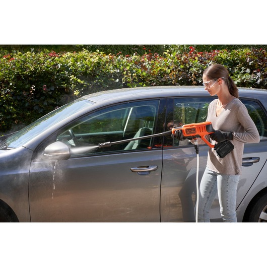 BLACKDECKER BCPW350E1 cordless pressure washer cleaning a gray car outdoors.