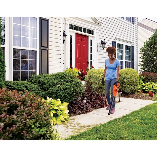 BLACKDECKER BCSW221E1 leaf blower held by person cleaning walkway in front yard garden.