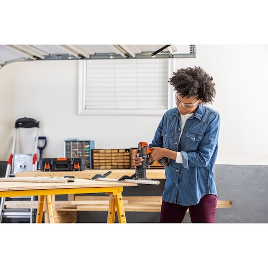 Person using BLACKDECKER BDCDMT1206KITC cordless tool on wood project in garage workspace.
