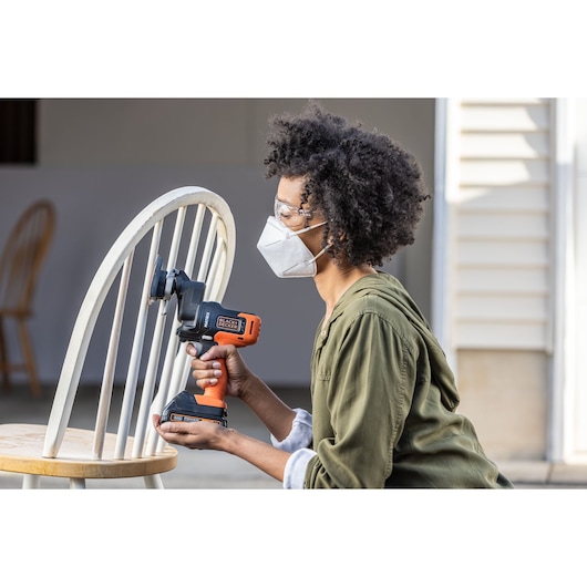 Photo of BLACKDECKER BDCDMT1206KITC drill being used to sand a wooden chair in a home setting.