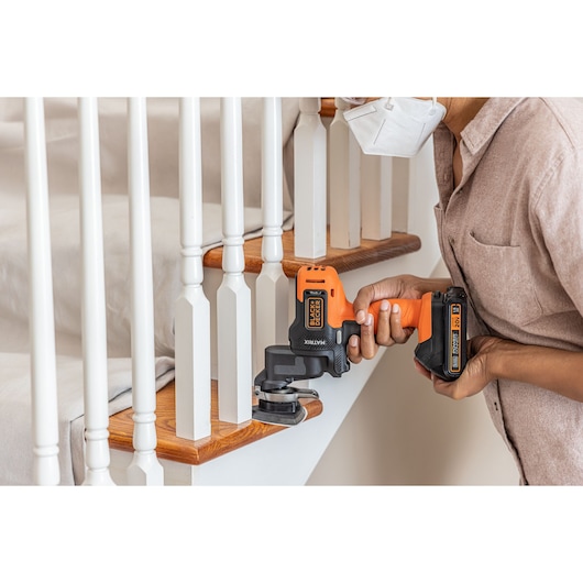 Photo of BLACKDECKER BDCDMT1206KITC cordless multi-tool sanding wooden stair railing.