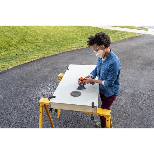 Photo of person using BLACKDECKER BDCDMT1206KITC cordless tool on wood project outdoors.