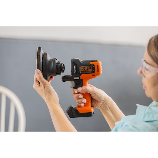 Photo of BLACK+DECKER BDCDMT1206KITC cordless power tool being fitted with attachment, close-up in hand.