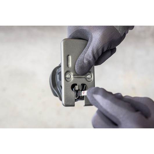 Photo of gloved hands adjusting a BLACKDECKER BDCDMT1206KITC power tool attachment, close-up view.