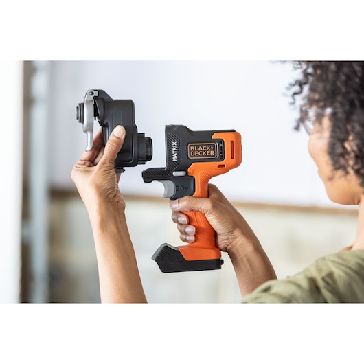 Photo of a person holding a BLACK+DECKER BDCDMT1206KITC cordless drill with MATRIX attachment system.