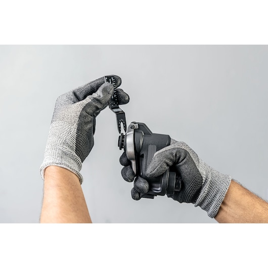 Photo of BLACKDECKER BDCMTO tool accessory held by gloved hands, showing installation detail.
