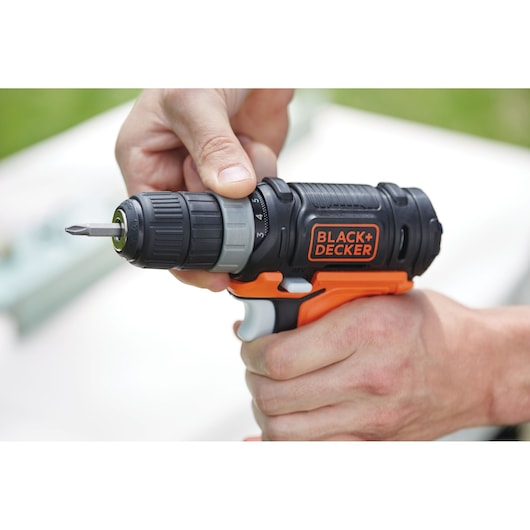 Photo of BLACKDECKER cordless drill BDCK502C1 in use, close-up of black and orange tool with visible bit.