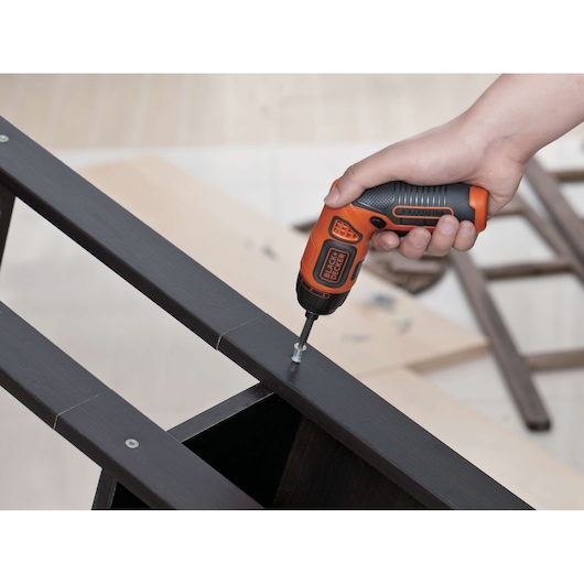 BLACKDECKER BDCS36F cordless screwdriver in use assembling dark wood furniture.