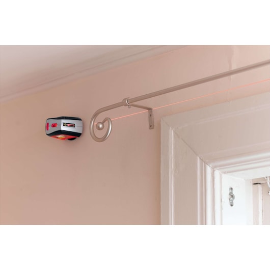 BLACKDECKER BDL220S laser level mounted on wall, projecting straight red line across light-colored room.