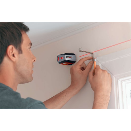 Photo of BLACKDECKER BDL220S laser level projecting a red line for marking wall mounting points near a door frame.