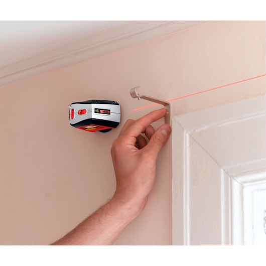 BLACKDECKER BDL220S laser level mounted on wall projecting red laser line above door frame.