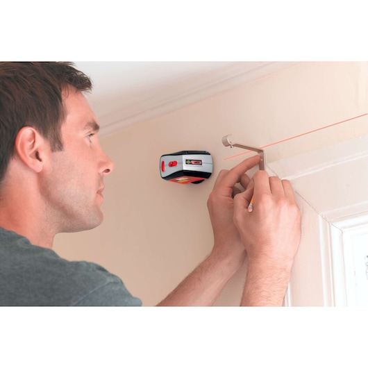BLACKDECKER BDL220S laser level projecting a straight red line on wall for precise alignment during installation.