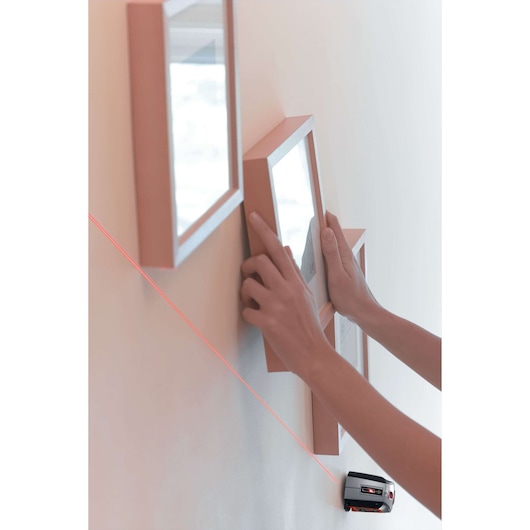 Photo of BLACKDECKER BDL220S laser level projecting a red line on a wall to align picture frames.