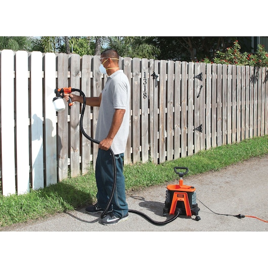 Photo of BLACKDECKER BDPH1200 paint sprayer used outdoors to paint a wooden fence.