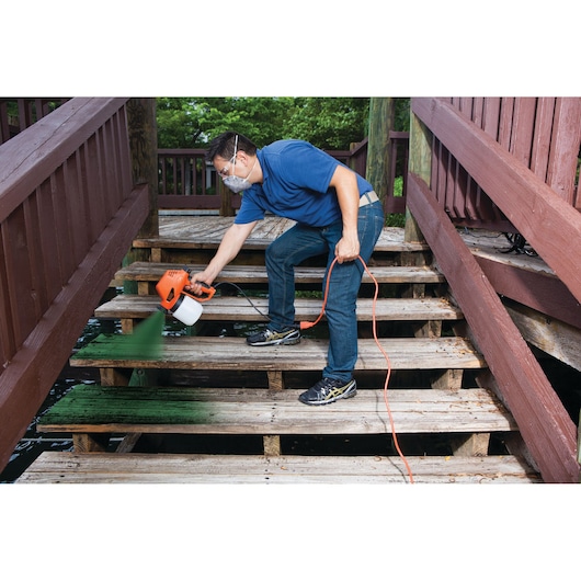 Photo of BLACKDECKER BDPS130 paint sprayer used to paint wooden stairs outdoors.