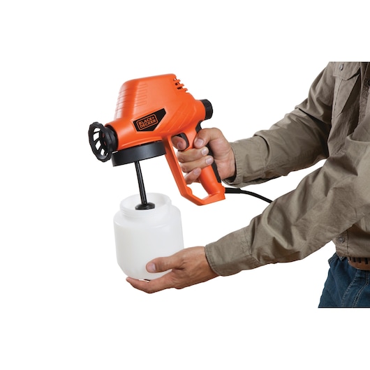 BLACKDECKER BDPS130 paint sprayer with orange body, shown in use on white background.