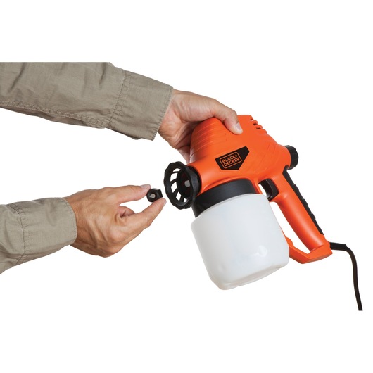 Photo of BLACKDECKER BDPS130 paint sprayer held by hands, showing nozzle adjustment, photographed against white background.