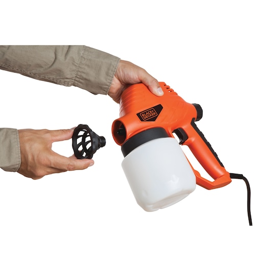 Photo of BLACK+DECKER BDPS130 paint sprayer, orange and black, side angle, being assembled by hands.