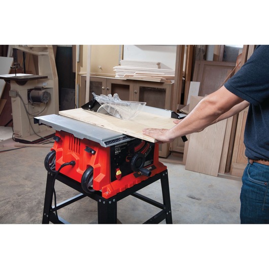 Photo of BLACKDECKER BDTS1800 table saw cutting wood, side view, in a workshop setting.