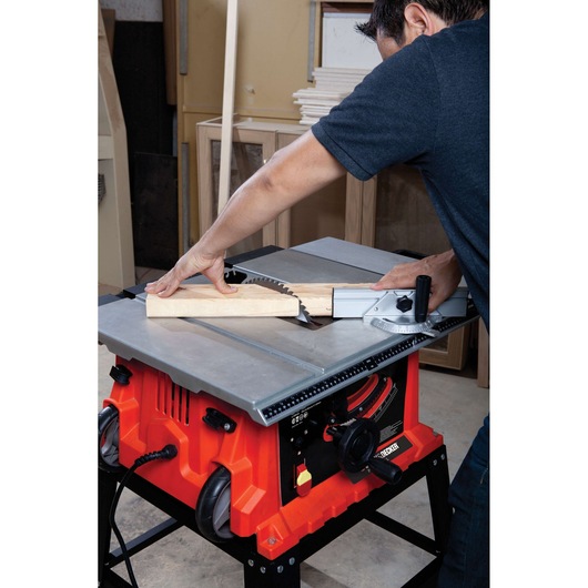 BLACKDECKER BDTS1800 table saw cutting wood, red body with silver top, workshop setting