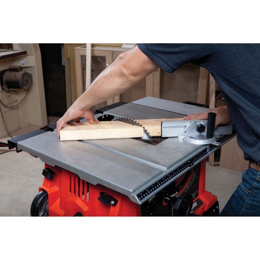 BLACKDECKER BDTS1800 table saw cutting wood, angled view showing silver surface and red base.