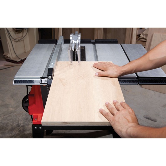 BLACKDECKER BDTS1800 table saw cutting light wood board, close-up of hands guiding material.
