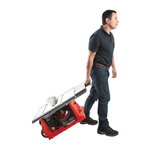 Photo of a person pulling a BLACKDECKER BDTS1800 portable table saw with wheels, side view, on white background.