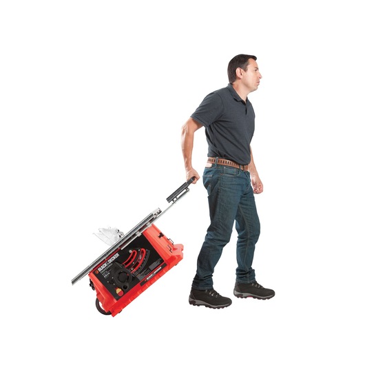 BLACKDECKER BDTS1800 table saw with handle and wheels being pulled by a person, side angle on white background.