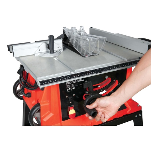 BLACKDECKER BDTS1800 table saw close-up, hand adjusting control knob, silver top, red base, white background.