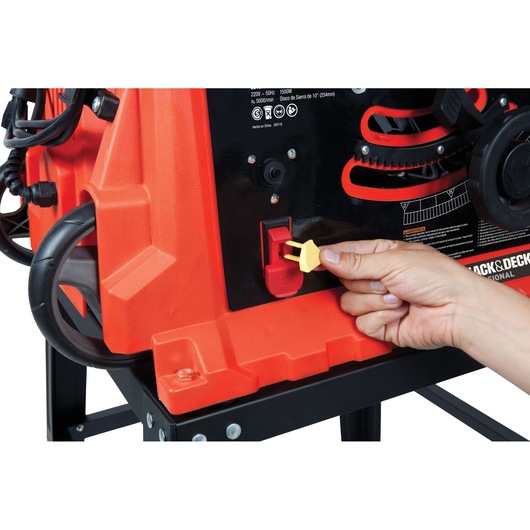 BLACKDECKER BDTS1800 table saw close-up, hand inserting yellow safety key into red switch, product side view.