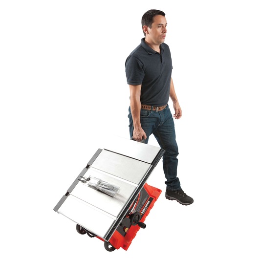 Photo of person wheeling a BLACKDECKER BDTS1800 table saw on white background, showing portable design.