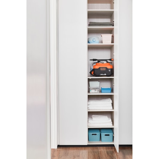 BLACKDECKER BEPW1600H pressure washer stored on a closet shelf with household items, front view.