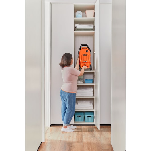 BLACKDECKER BEPW1800T pressure washer stored vertically in a closet shelf with household items around.