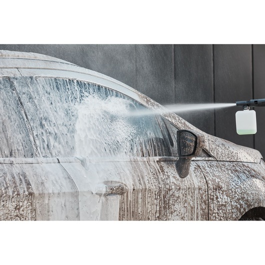 BLACKDECKER BEPW2200 pressure washer spraying foam on dirty car side, closeup, front side view.