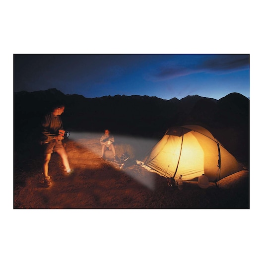 Photo of BLACKDECKER BSL100 spotlight used at a campsite at night, with a lit tent and two people outdoors.