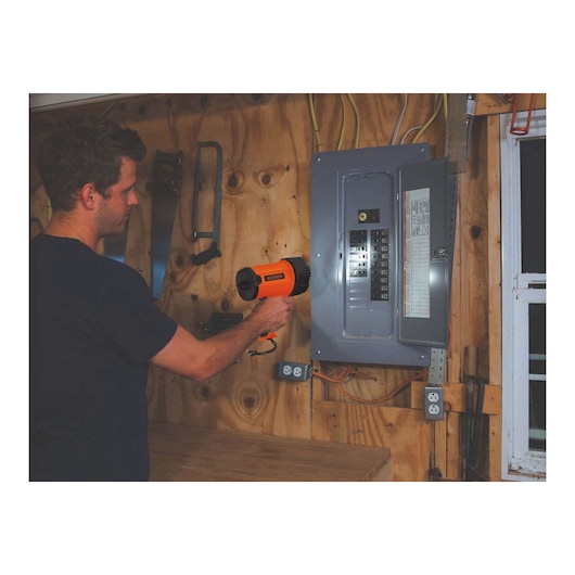 BLACKDECKER BSL100 handheld spotlight used near an electrical panel in a workshop setting.
