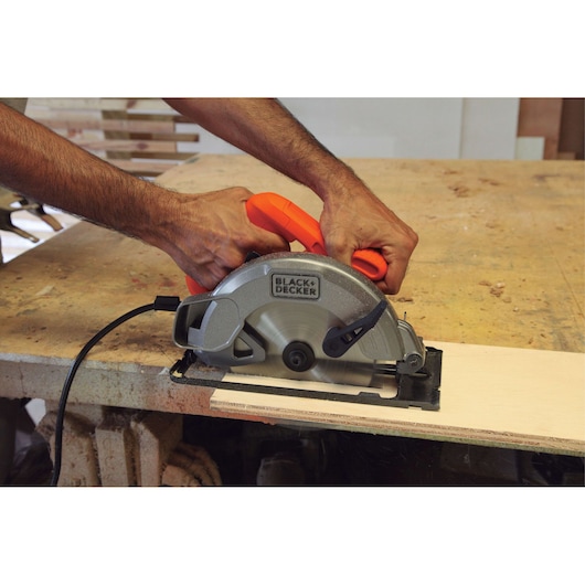 BLACKDECKER CS1004 circular saw in use cutting wood, with visible orange handle and silver blade.