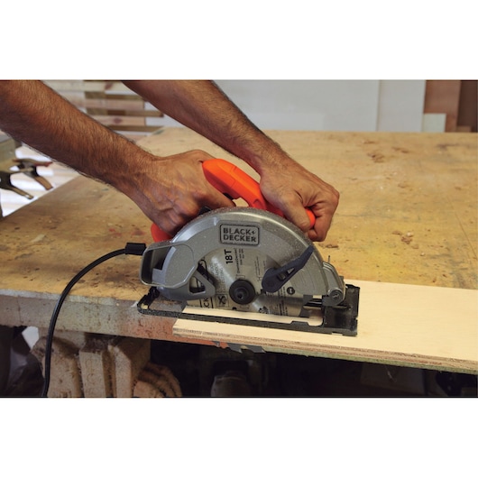 BLACKDECKER CS1004 circular saw cutting wood on workbench, close-up side angle.