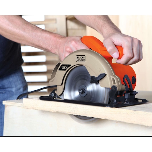 BLACKDECKER CS1024 circular saw in use cutting wood, orange and gold body, 1500 watts visible.