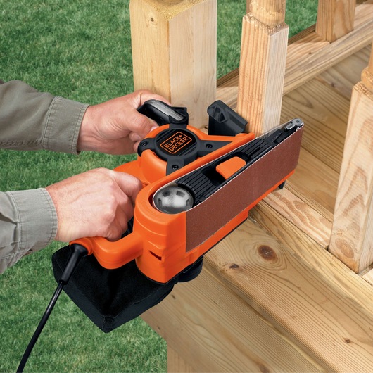 Photo of BLACKDECKER DS321 belt sander being used to sand wooden railing outdoors.