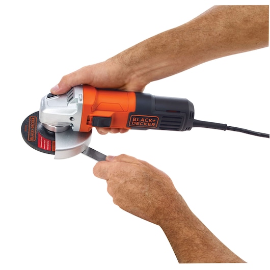 Photo of BLACKDECKER G650 angle grinder in use, orange and black body, cutting metal, side view.